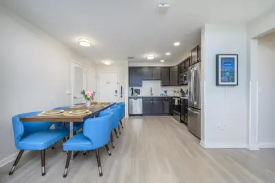 a kitchen and dining room with a table and blue chairs at Epic Universe Brand New Modern Vista Cay Reserve Condo - 6005 in Orlando