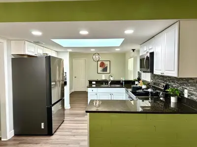 a kitchen with a black refrigerator and white cabinets at Orlando Luxe Retreat with Private Pool in Orlando