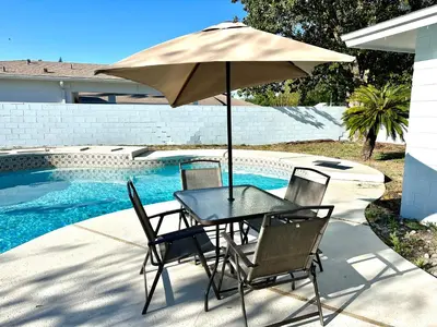 a table and chairs with an umbrella next to a pool at Orlando Luxe Retreat with Private Pool in Orlando