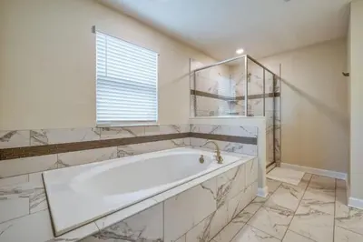 a white bathroom with a tub and a window at 6Q/6B | Piscina Privativa | Game Room Temático in Kissimmee