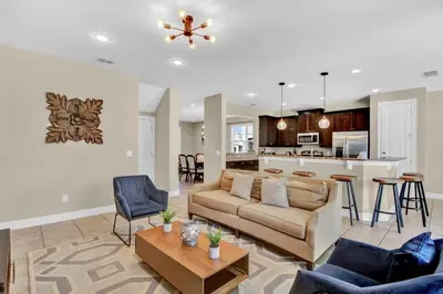 a living room with a couch and a kitchen at Relaxing 6BR Home w Pool Near Disney in Orlando