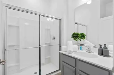 a white bathroom with a shower and a sink at SUPER RITZY - 9BDRs-9BAs w Theme Rooms LOFT & POOL in Orlando