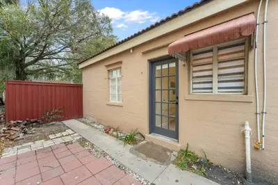 a house with a red fence and a window at SUPER BOHO - Lake Toho Timeless Charm in Kissimmee