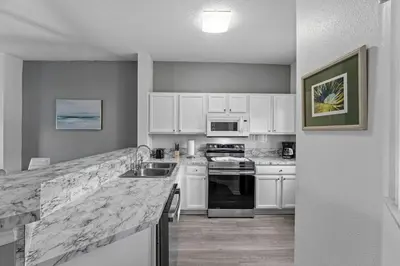 a kitchen with white cabinets and a marble counter top at SUPER YES - MANY AMENITIEs RELAX GYM COURTs in Kissimmee