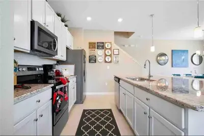 a large kitchen with white cabinets and a sink at SUPER CHIC - 4 Bedroom TOWNHOME IN DISNEY AREA in Kissimmee