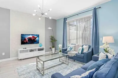 a living room with a blue couch and a tv at SUPER DOPE- Home w POOL & AMENITIEs in Kissimmee