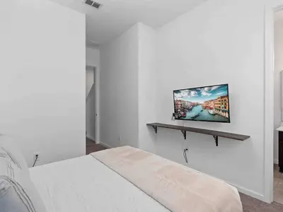 a white bedroom with a bed and a tv on the wall at SUPER JUMBO - 12BD 12BAs SLEEPs 34 - w AMENITIEs in Kissimmee