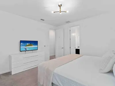 a white bedroom with a bed and a flat screen tv at SUPER JUMBO - 12BD 12BAs SLEEPs 34 - w AMENITIEs in Kissimmee