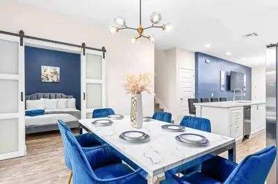 a dining room with a table and blue chairs at SUPER EPIC- SLEEPs 32 TWO Separate Townhomes in Kissimmee