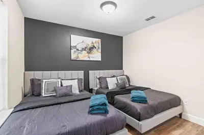 a bedroom with two beds and a black wall at SUPER EPIC- SLEEPs 32 TWO Separate Townhomes in Kissimmee