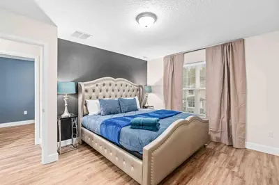 a bedroom with a large bed with blue pillows at SUPER EPIC- SLEEPs 32 TWO Separate Townhomes in Kissimmee