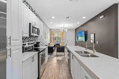 a kitchen with a sink and a living room at SUPER EPIC- SLEEPs 32 TWO Separate Townhomes in Kissimmee