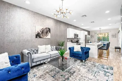 a living room with blue couches and a kitchen at SUPER POSH- SLEEPs 16 wDESIGNs & NEAR Disney in Kissimmee