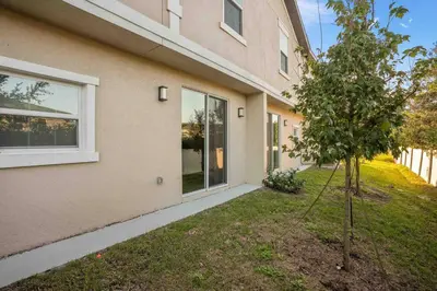 a house with a tree next to a building at SUPER POSH- SLEEPs 16 wDESIGNs & NEAR Disney in Kissimmee