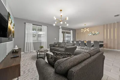 a living room with a couch and a dining room at SUPER BLISS - 9BDR SLEEPs 30 - MOVIE ROOM & POOL in Kissimmee