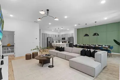 a living room with a couch and a table and a kitchen at SUPER CIELO - 12BDR 11BAs - FUN THEME w POOL in Orlando