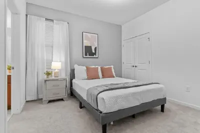 a white bedroom with a bed and a night stand at SUPER GIANT - 12BD 12BAs - SLEEP 38 & NEAR DiSNEY in Kissimmee