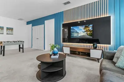 a living room with a couch and a tv on a wall at SUPER GIANT - 12BD 12BAs - SLEEP 38 & NEAR DiSNEY in Kissimmee