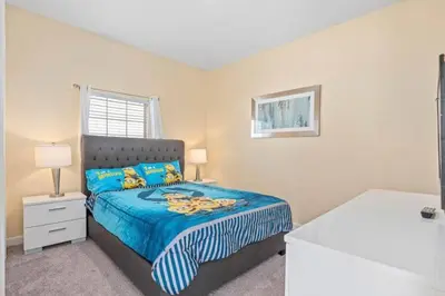 a bedroom with a bed with a blue comforter at Super Chill - 5 Bedrooms WPOOls in Kissimmee