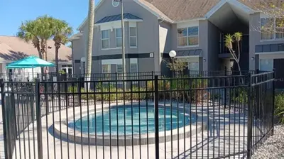 a fence around a swimming pool in front of a house at Two bed condo in Parkway Palms Resort condo in Orlando
