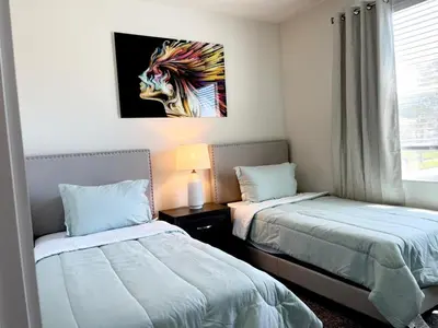 a bedroom with two beds and a painting on the wall at Serenity Townhome Getaway 4 bed 3 bath home near Disney in Clermont FL in Orlando