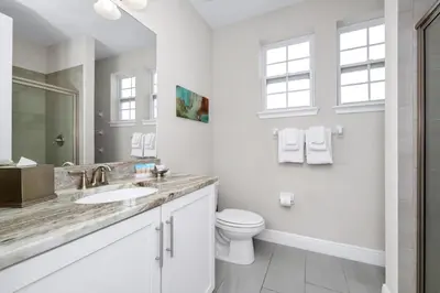 a white bathroom with a sink and a toilet at Home With Splash Pad And Slide, Movie Theater & Game Room With Waterpark & Resort Access - 417Sf in Kissimmee