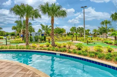 a swimming pool with palm trees in a resort at Apartamento Moderno 2Q | Quarto Temático do Mickey in Kissimmee