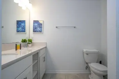 a white bathroom with a toilet and a sink at Apto 2Q Vista Lago | 10 min Disney in Kissimmee
