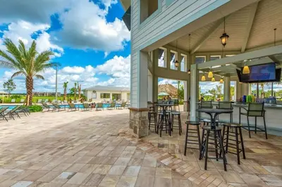 a patio with tables and chairs and a bar at Apto 2Q Vista Lago | 10 min Disney in Kissimmee