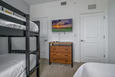 a bedroom with two bunk beds and a wooden dresser at Apartamento 3BR/2BA – A 10 Min dos Parques Disney! in Kissimmee