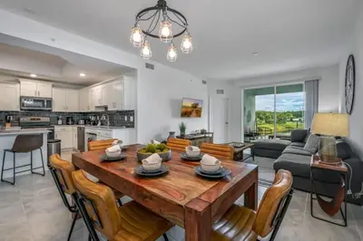 a kitchen and living room with a wooden table and chairs at Apartamento 3BR/2BA – A 10 Min dos Parques Disney! in Kissimmee