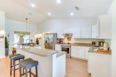 a kitchen with white cabinets and bar stools at Near Parks and Lakes Sorrento Home with Pool and Yard! in Sorrento