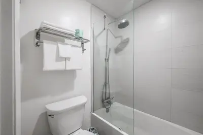 a white bathroom with a shower and a toilet at Modern- 2 Queen bed suite with pool near Disney World in Kissimmee