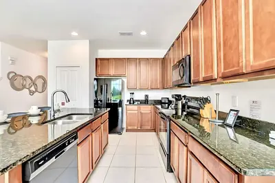 a large kitchen with wooden cabinets and appliances at Family Home with Cinema Pool and BBQ Near Disney in Kissimmee