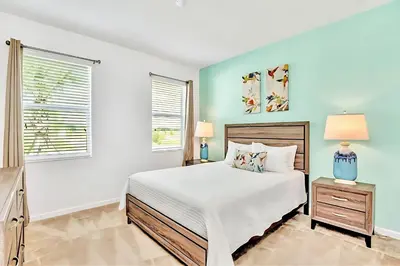 a white bedroom with a bed and two windows at Family Home with Cinema Pool and BBQ Near Disney in Kissimmee