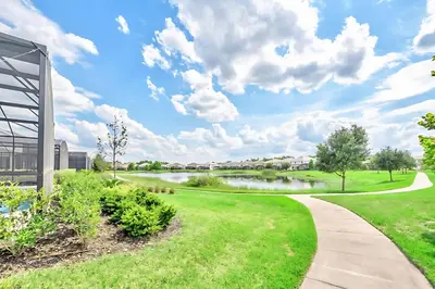 a walkway through a park with a lake at Family Home with Cinema Pool and BBQ Near Disney in Kissimmee