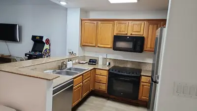 a kitchen with wooden cabinets and a sink and a refrigerator at Orlando Blue Heron 1 Mile From Disney 11th floor in Orlando