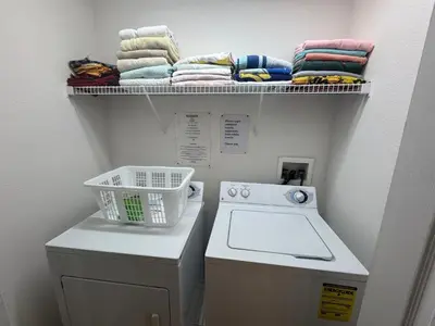 a laundry room with a washing machine and a shelf with towels at Sunset Villa – Your Gateway to a Magical Florida Vacation! in Kissimmee