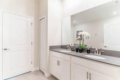 a white bathroom with two sinks and a mirror at FLASH SALE Pvt Pool and Spa Home at Storey Lake in Kissimmee