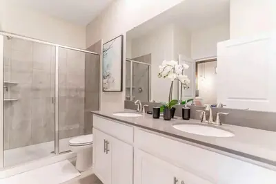 a white bathroom with two sinks and a shower at FLASH SALE Pvt Pool and Spa Home at Storey Lake in Kissimmee