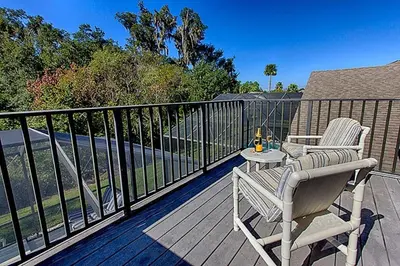 a rocking chair and a table on a balcony at Charming 4-Bedroom Villa with Pool & Spa, Only 15 Minutes from Disney! in Kissimmee