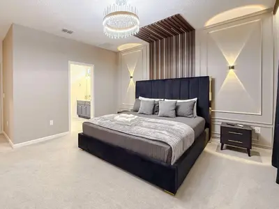 a bedroom with a large bed and a chandelier at Sophisticated 9 bedroom close to Disney in Kissimmee
