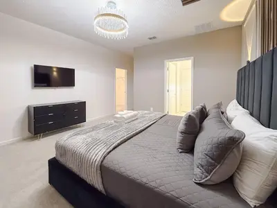 a bedroom with a large bed and a flat screen tv at Sophisticated 9 bedroom close to Disney in Kissimmee