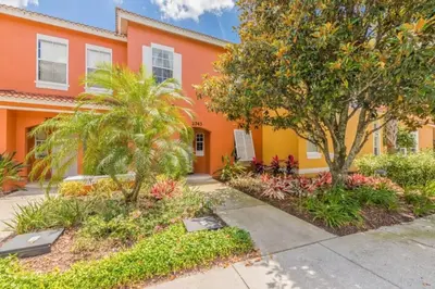 an orange building with trees and plants in front of it at Flash 20 Off Townhome at Emerald Island Resort in Kissimmee