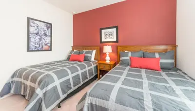two beds in a bedroom with a red wall at Special Offer Elegant Townhome at West Lucaya in Kissimmee