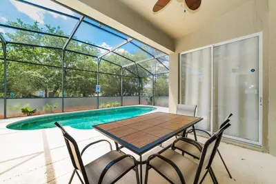 a dining room with a table and chairs next to a swimming pool at Special Offer Beautiful Pvt Pool home in Kissimmee