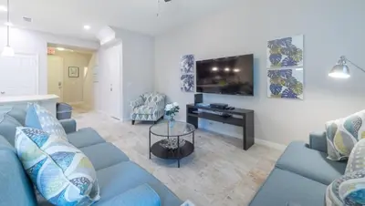 a living room with a blue couch and a tv at Special Offer Cozy Retreat at Compass Bay in Kissimmee