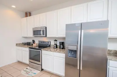 a kitchen with white cabinets and a stainless steel refrigerator at Special Offer Fantastic Townhome with Pvt Pool and Lake view near Disney in Kissimmee