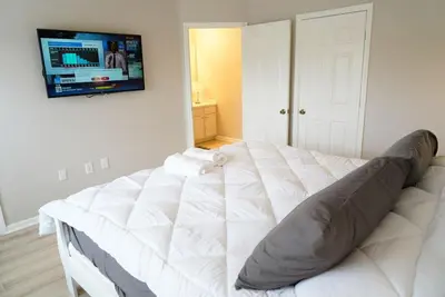a white bed in a room with a tv on the wall at New Luxury Disney Townhome at Windsor Hills Resort, 3BED 3BATH, Private Pool Parking WiFi Included in Orlando