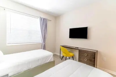 a bedroom with two beds and a desk with a television at Stylish Apartment at Vista Cay in Orlando